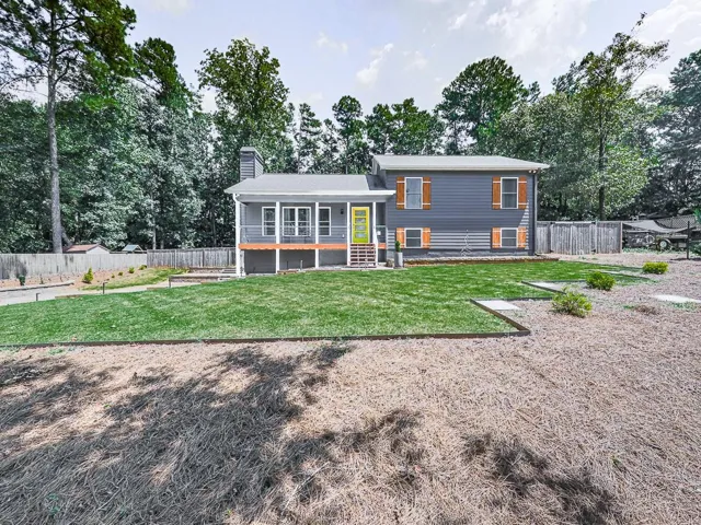 Gray siding exterior with white trim, covered porch with white railing, and a vibrant yellow front door