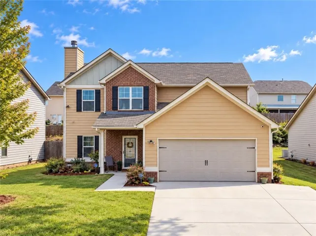Two-story exterior with brick and siding facade, an attached garage, and a concrete driveway
