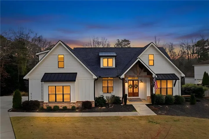 Modern inspired farmhouse with a standing seam roof, board and batten siding, a shingled roof, and a front lawn