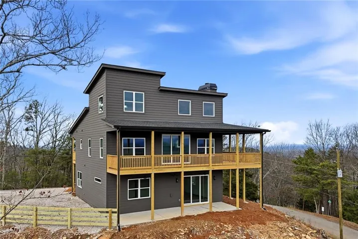 Multi-story exterior with dark gray siding, multiple windows, and a covered balcony