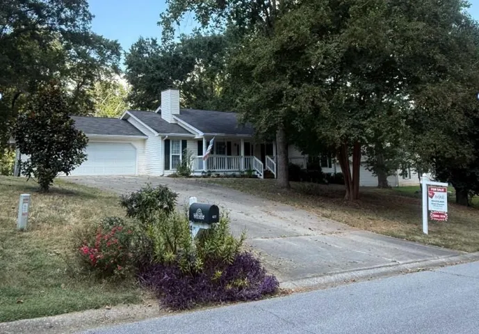 White exterior with dark shutters, covered front porch, and an attached two-car garage