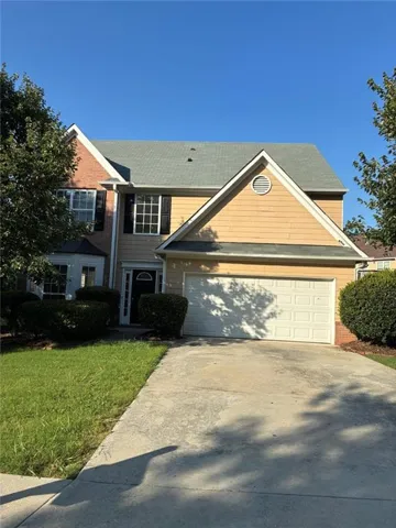 Two-story residence featuring a brick and siding exterior, an attached two-car garage, an asphalt shingle roof, a concrete driveway, and established front landscaping