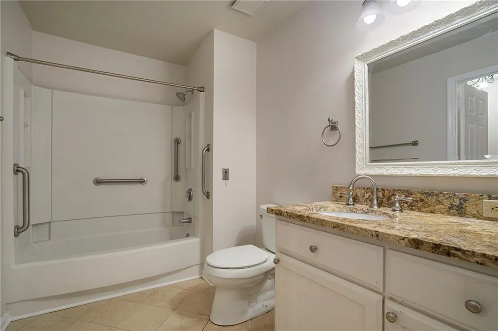 Full bathroom featuring toilet, vanity with extensive cabinet space, tile floors, and shower / tub combination