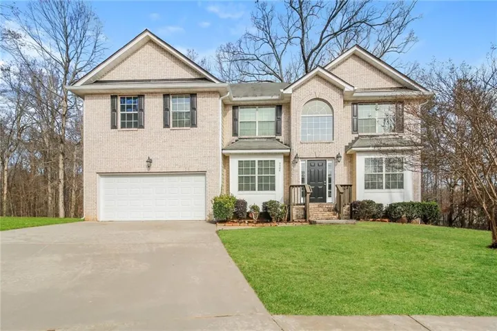Traditional-style house featuring concrete driveway, a garage, a front yard, and brick siding