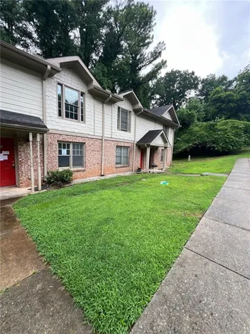 Exterior facade with a combination of brick and siding, multiple windows, and a paved walkway