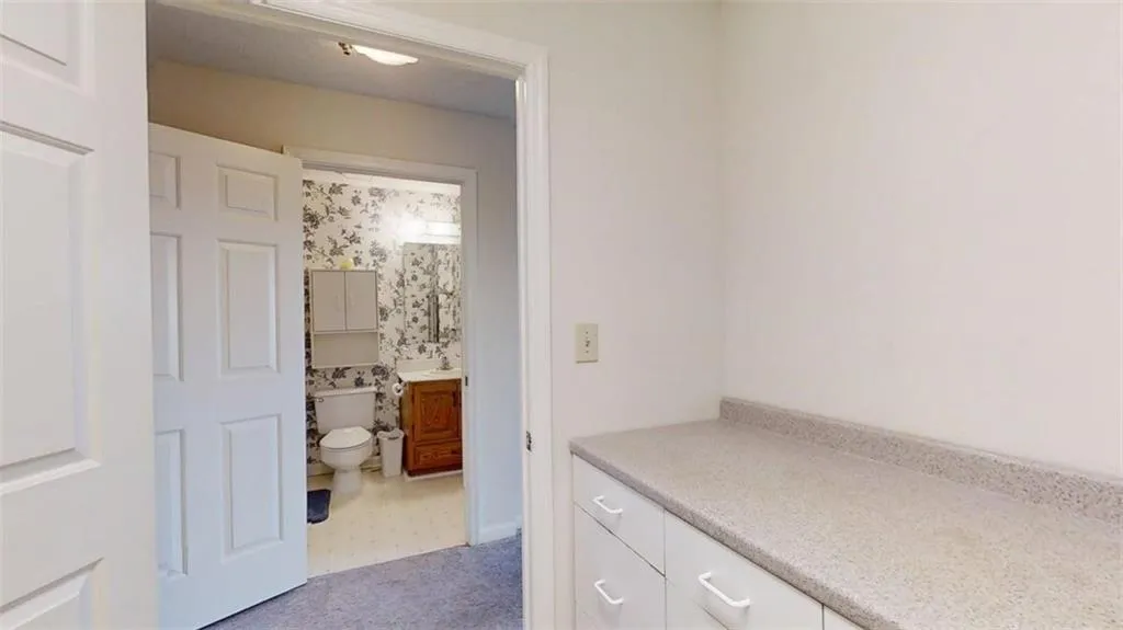 Bathroom with vanity, wallpapered walls, and light flooring