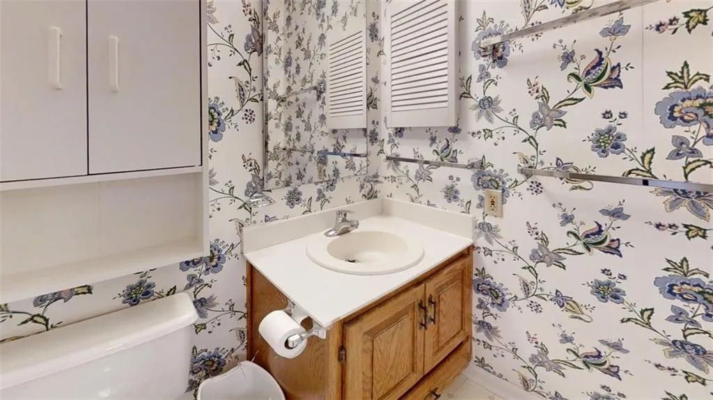 Half bathroom featuring wallpapered walls and vanity