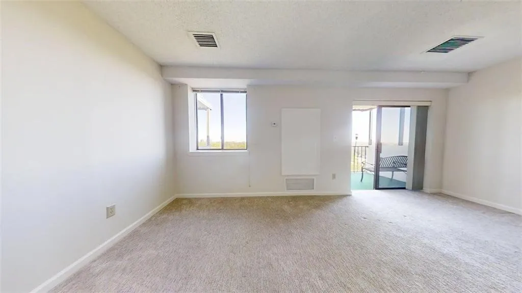 Unfurnished room with a textured ceiling, healthy amount of natural light, and light carpet