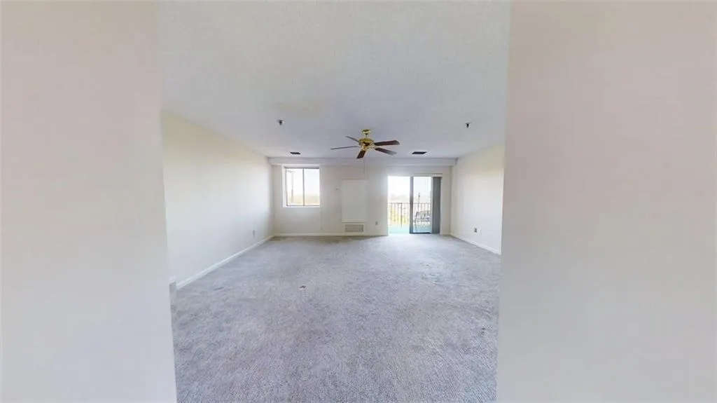 Empty room featuring a ceiling fan and carpet