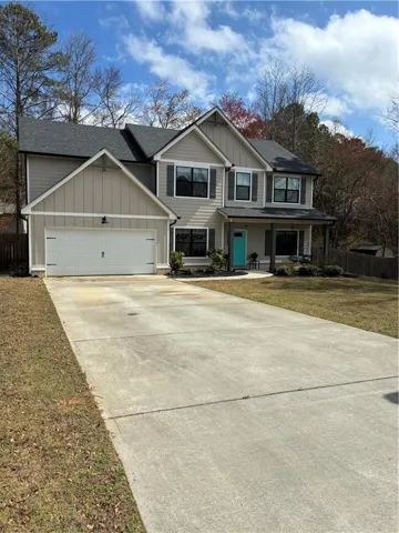 Craftsman-style house featuring board and batten siding, a porch, driveway, a garage, and roof with shingles