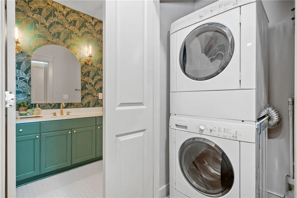 Laundry room with wallpapered walls and stacked washer / dryer