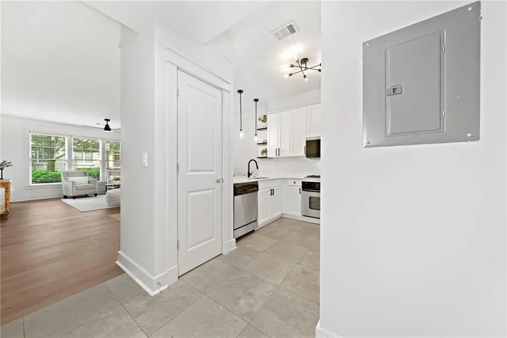 Hallway with electric panel, baseboards, a sink, and light tile patterned floors