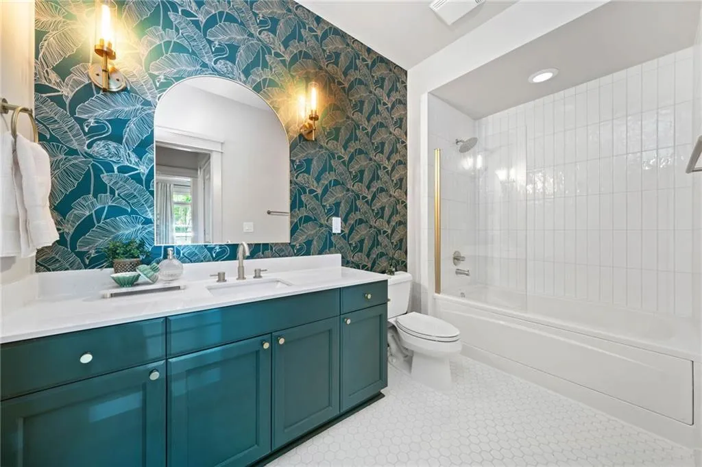 Bathroom featuring wallpapered walls, vanity, toilet, and  shower combination