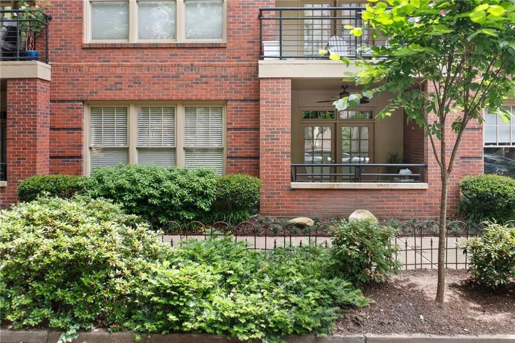 Doorway to property with a balcony, brick siding, and a ceiling fan