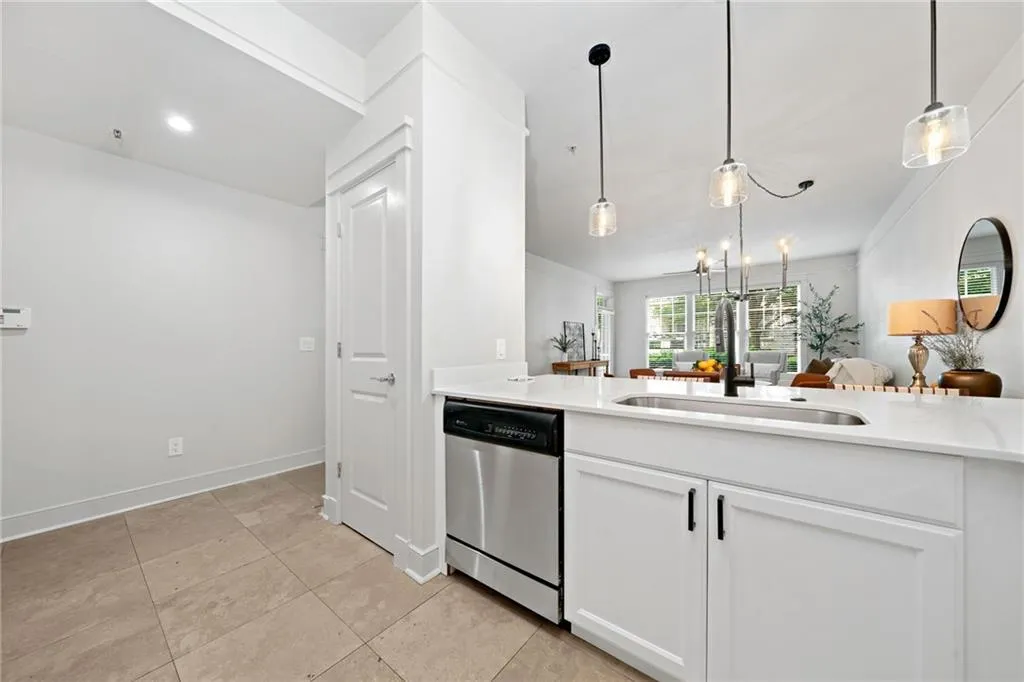 Kitchen with dishwasher, a sink, decorative light fixtures, white cabinets, and light countertops