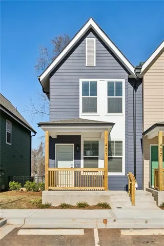 Gable roofline, horizontal siding exterior, covered porch with wood railing, concrete steps, and two dedicated parking spaces