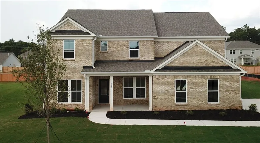 Brick exterior with a covered porch, gabled roofline, and established landscaping