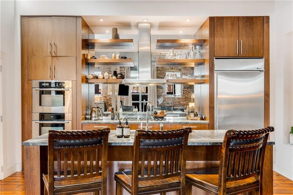 Indoor wet bar with light wood-style flooring, appliances with stainless steel finishes, open shelves, island range hood, and modern cabinets