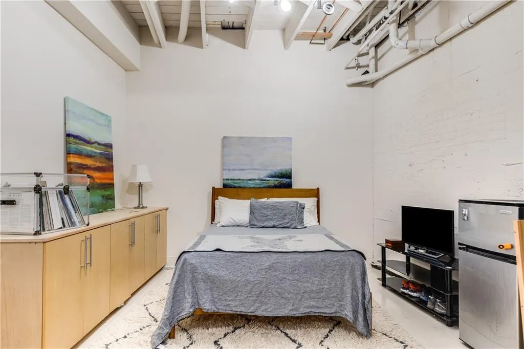 Bedroom with freestanding refrigerator and beam ceiling