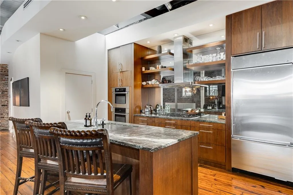 Kitchen featuring open shelves, appliances with stainless steel finishes, light wood finished floors, and dark stone counters