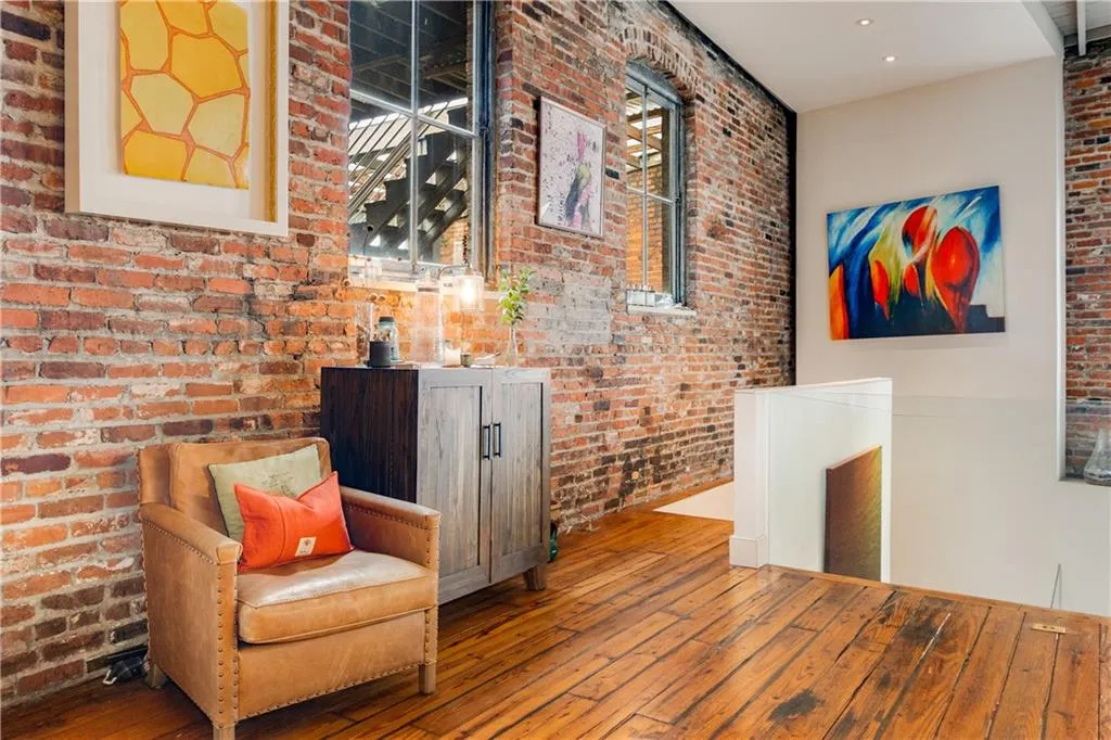 Living area with hardwood / wood-style flooring and brick wall