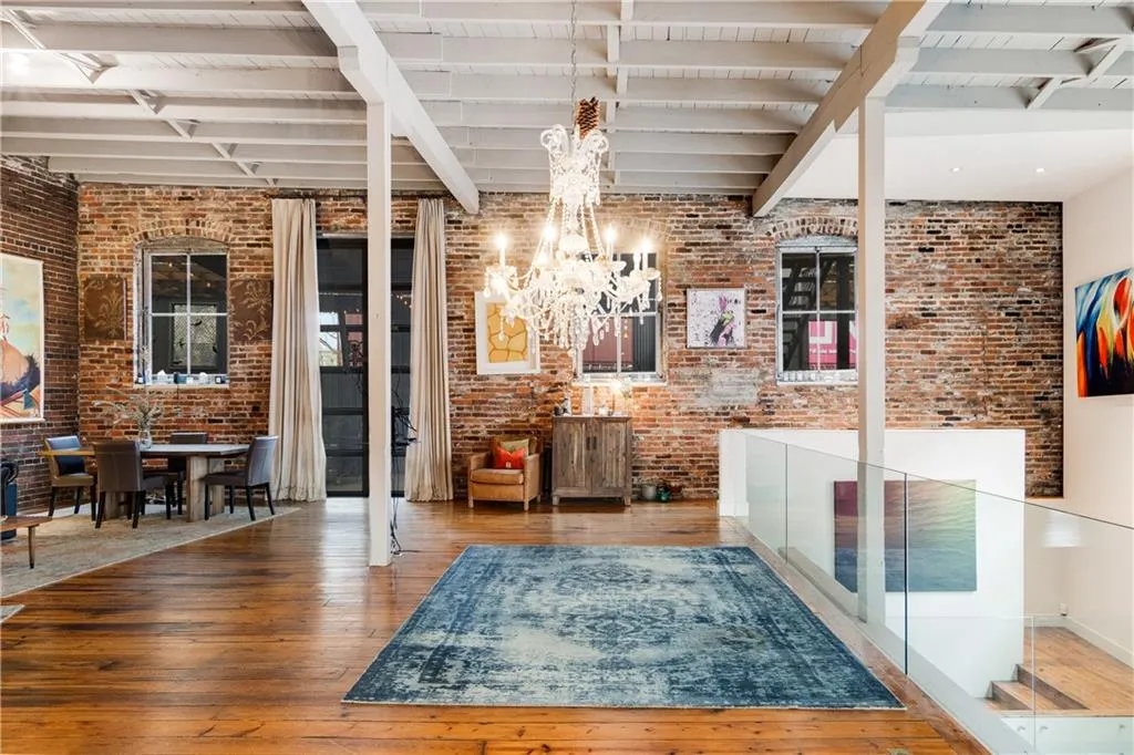 Bar area featuring beamed ceiling, hardwood / wood-style flooring, brick wall, a chandelier, and decorative light fixtures