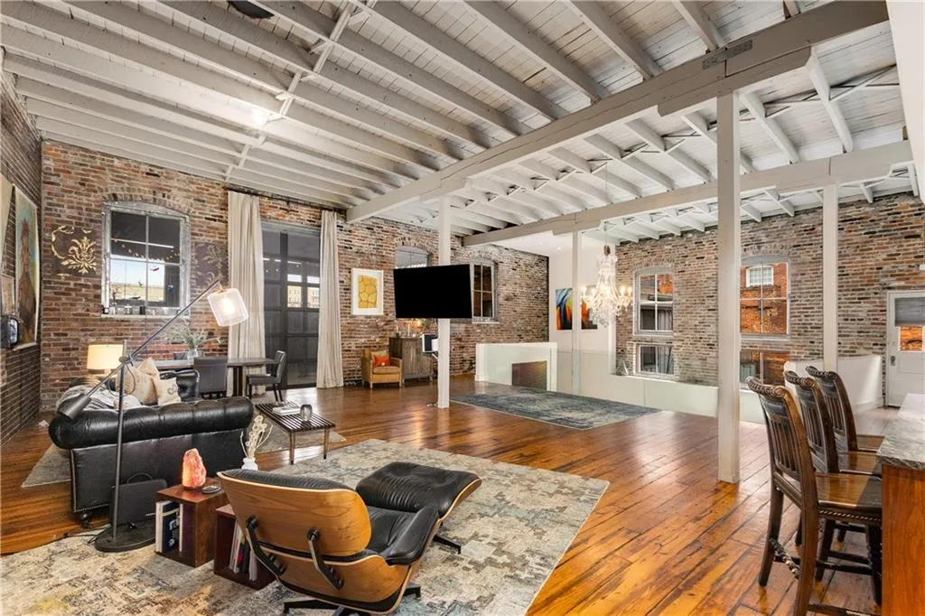 Living area with brick wall, beamed ceiling, hardwood / wood-style flooring, and a fireplace