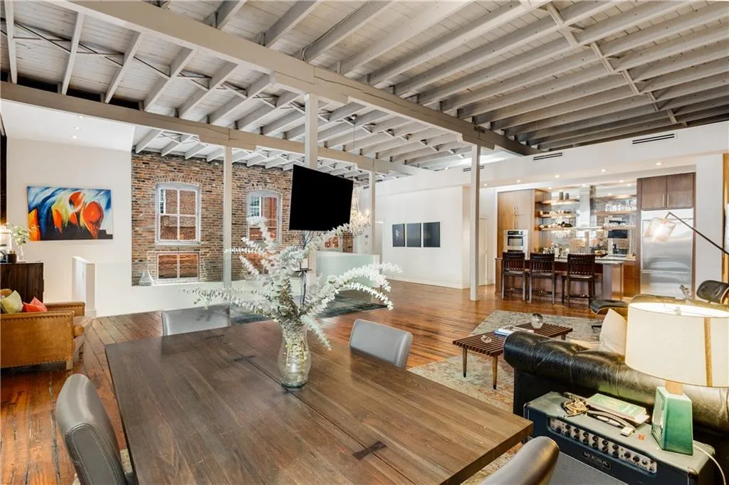 Dining space with bar area, beamed ceiling, hardwood / wood-style floors, and brick wall