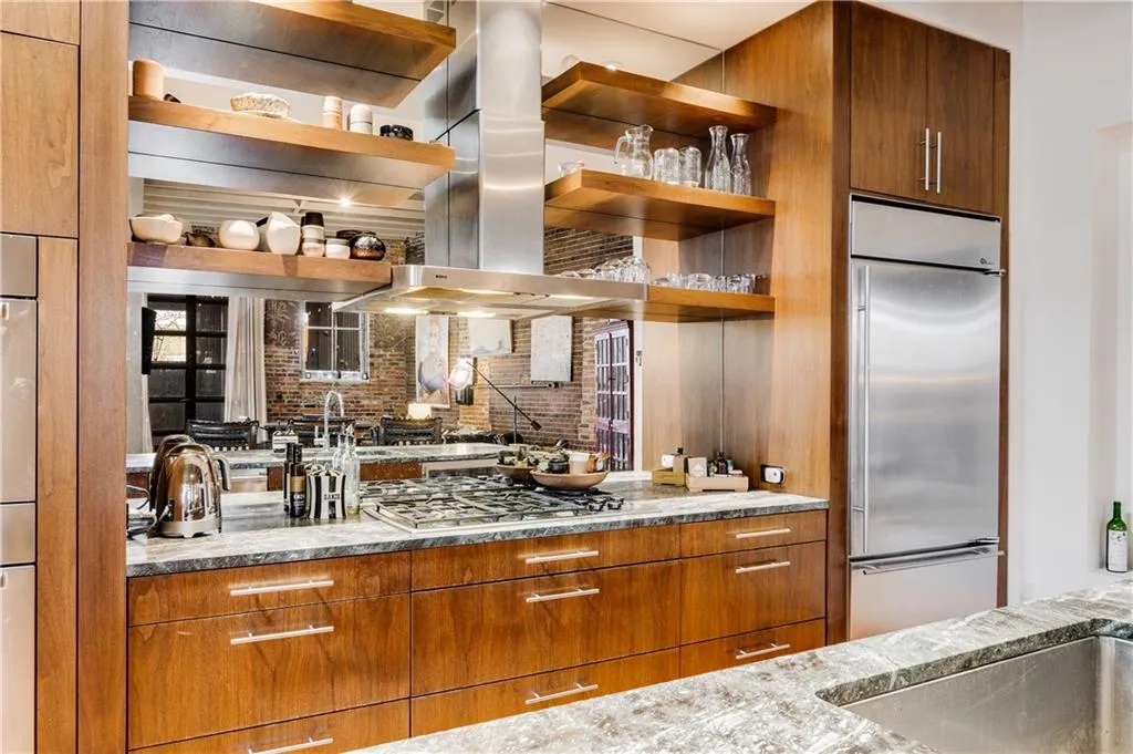 Kitchen with brown cabinetry, open shelves, stainless steel built in refrigerator, and island range hood