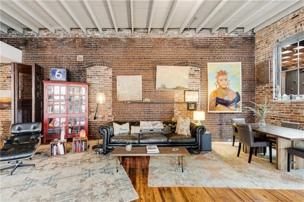 Living room with brick wall, hardwood / wood-style flooring, beam ceiling, and a towering ceiling
