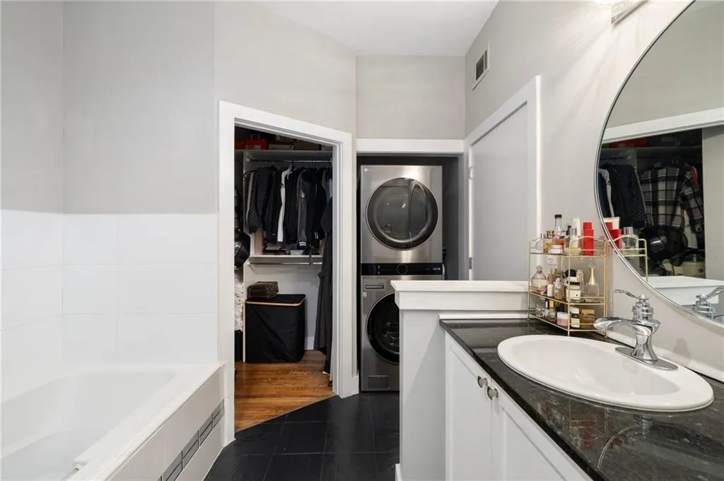 Full bathroom featuring stacked washer / dryer, a spacious closet, vanity, and tile patterned floors