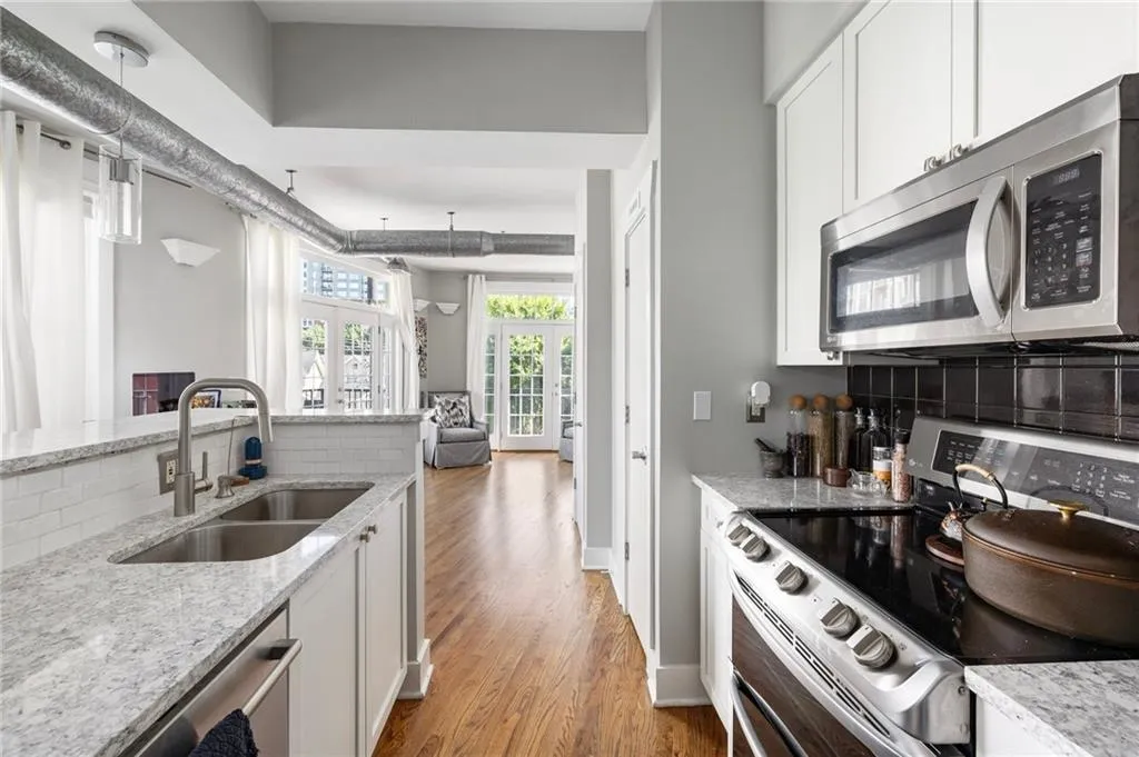 Kitchen featuring stainless steel appliances, tasteful backsplash, light wood-type flooring, and white cabinets