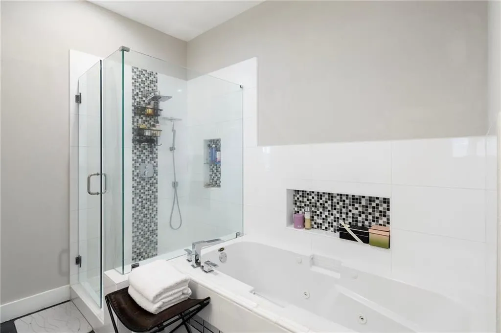 Bathroom featuring a shower stall, a jetted tub, and marble look tile flooring