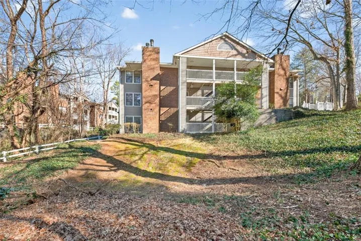 Multi-story residence featuring brick and siding exterior, multiple balconies with white railings, and prominent brick chimneys