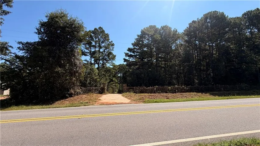 Wooded lot with a gravel driveway and partial wood fencing