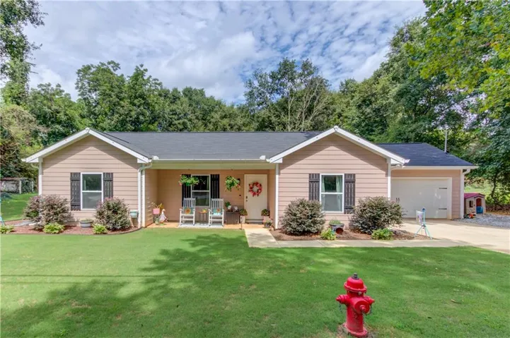 Single-story residence featuring a covered front porch, attached garage, and dark-finished shutters