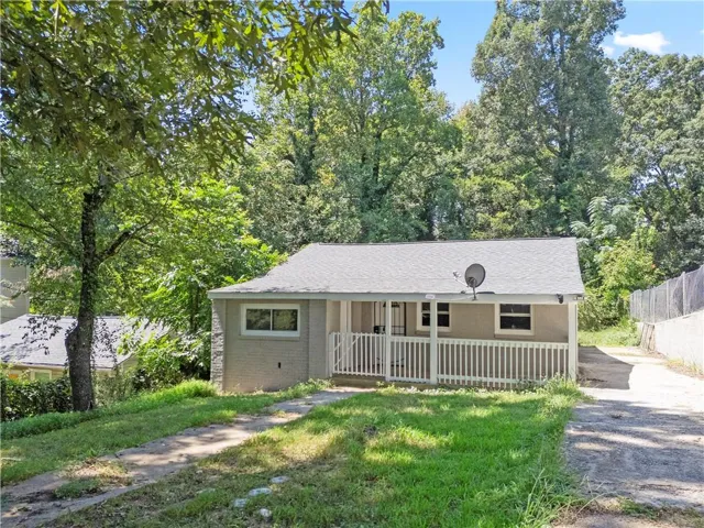 Charming ranch-style home featuring a covered front porch with white railings, updated siding, and multiple windows allowing natural light
