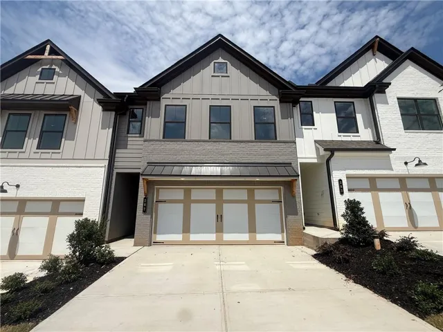 Modern townhome exterior featuring a combination of white brick, vertical siding, and horizontal siding