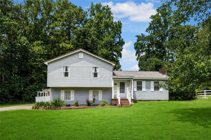 Split-level residence featuring light blue siding with white trim and shutters