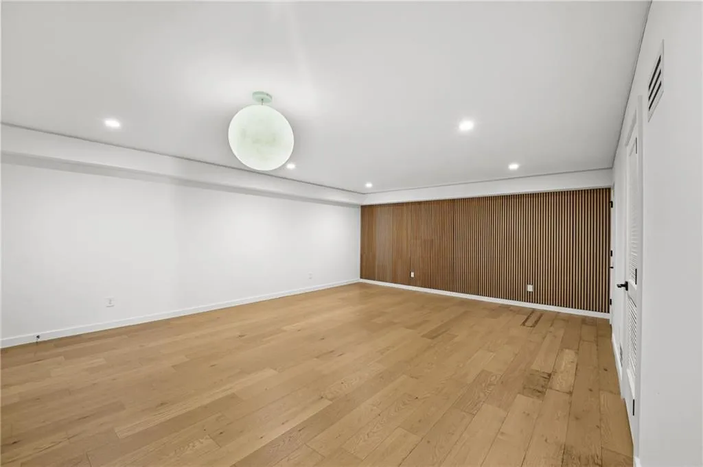 Recessed lighting, wood-finish flooring, accent wall with vertical wood paneling, flush-mount ceiling light
