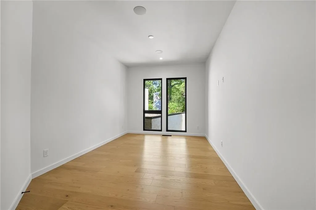 Recessed ceiling lighting, light wood-finish flooring, and two large windows with black frames