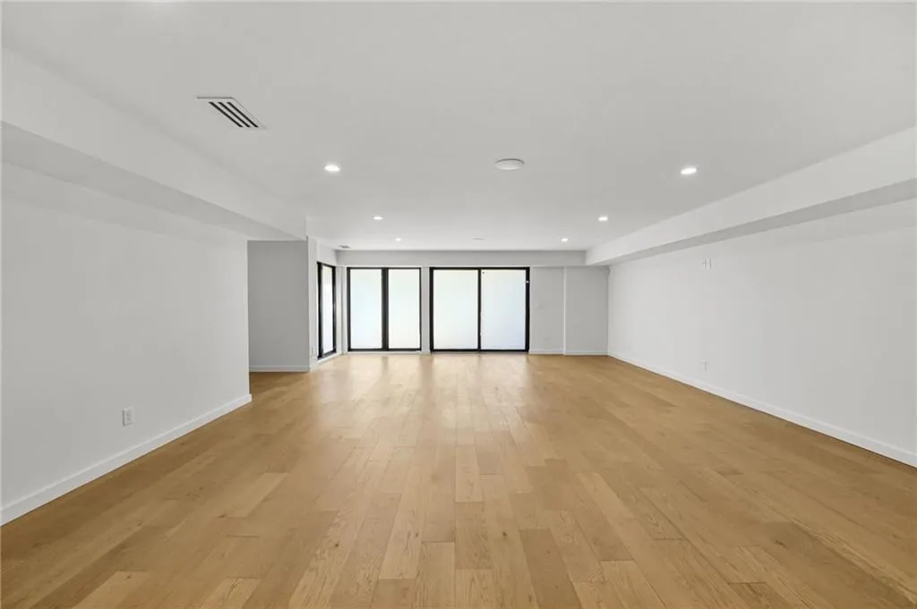 Expansive room with wood-finish flooring, recessed lighting, and multiple sliding glass doors