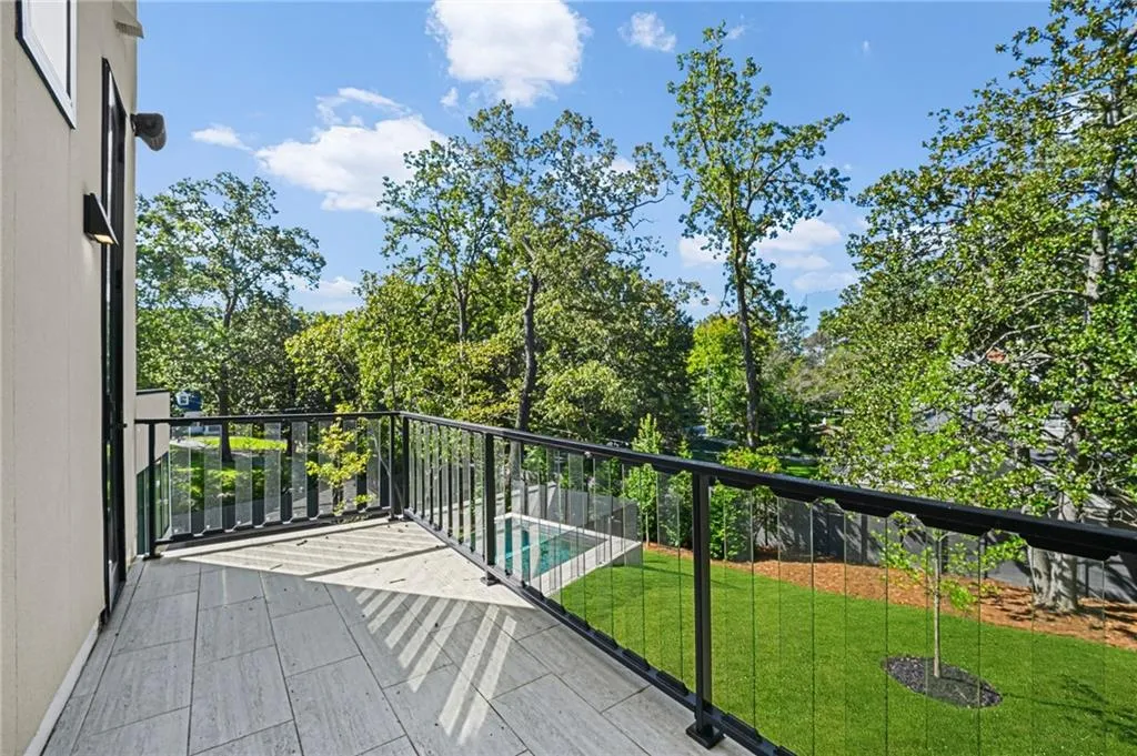 Outdoor balcony with tile flooring, glass panel railing, and integrated wall lighting