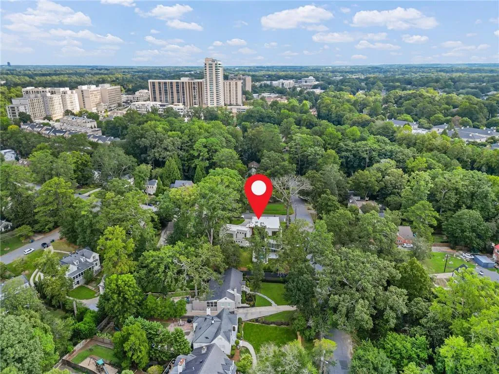 Aerial overview of the property amidst lush green trees, with urban architecture visible in the background