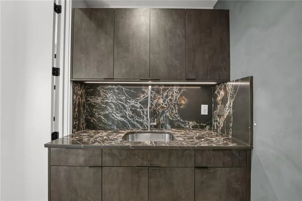 Built-in cabinetry with integrated sink, stone countertop, and matching stone backsplash