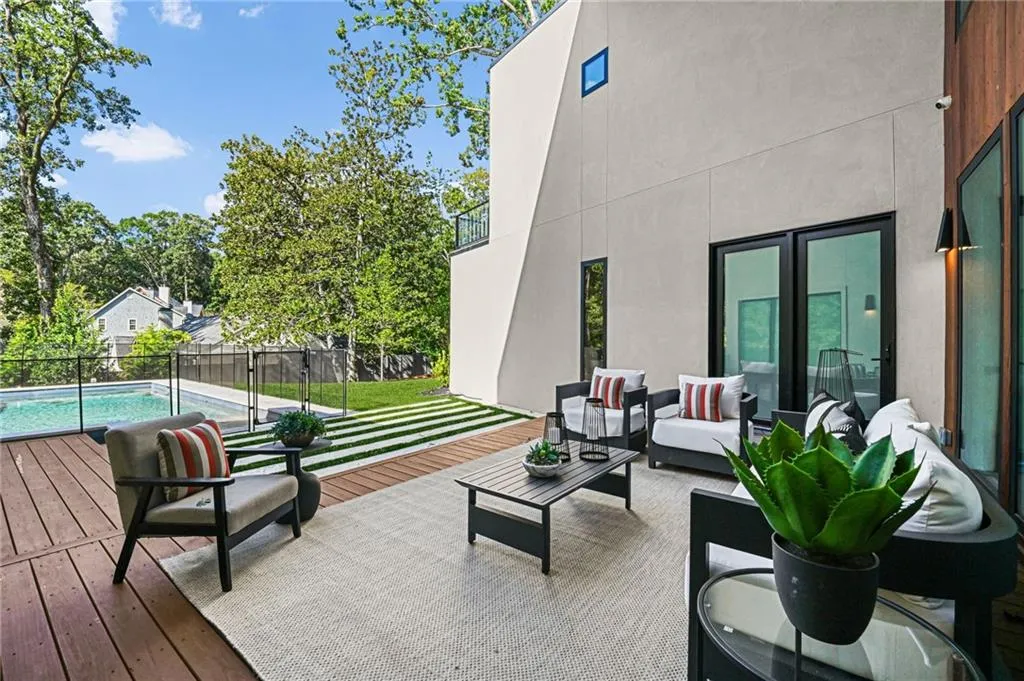 Expansive outdoor living area featuring a wooden deck, integrated swimming pool with safety fencing, and a combination of stucco and wood-paneled exterior finishes