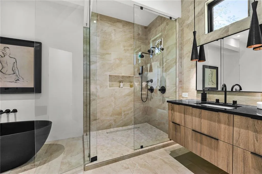 Glass-enclosed shower with a recessed niche, black matte fixtures, and stone-look tile