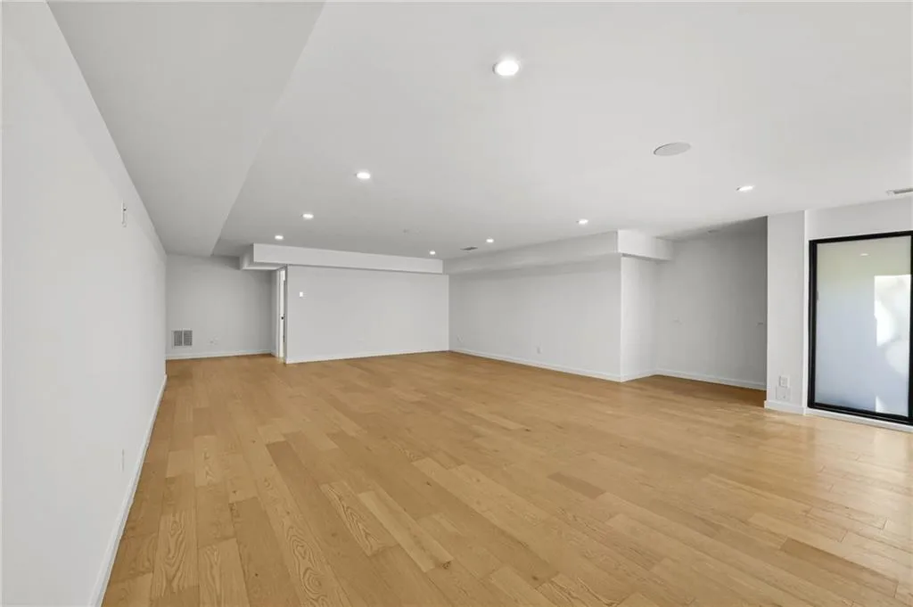 Expansive room featuring wood-finish flooring, recessed lighting, and a large black-framed window