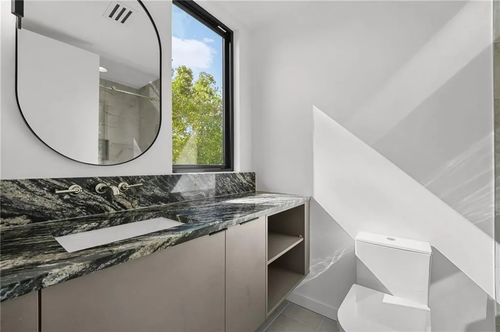 Wall-mounted vanity with a stone countertop, built-in rectangular sink, and a black-framed mirror