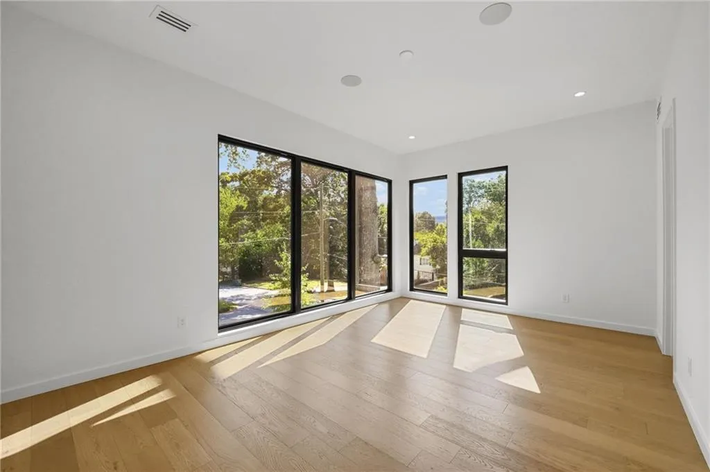 Expansive window array, light wood-finish flooring, recessed lighting, and integrated ceiling speakers